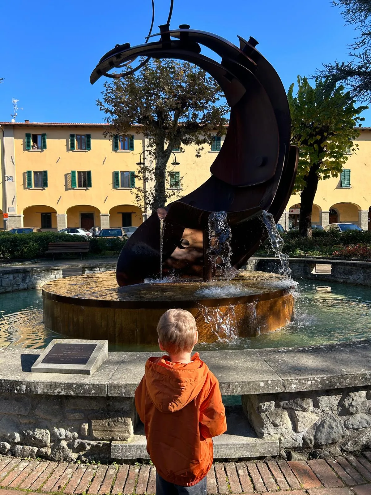 Bambino davanti a una fontana in una piazza