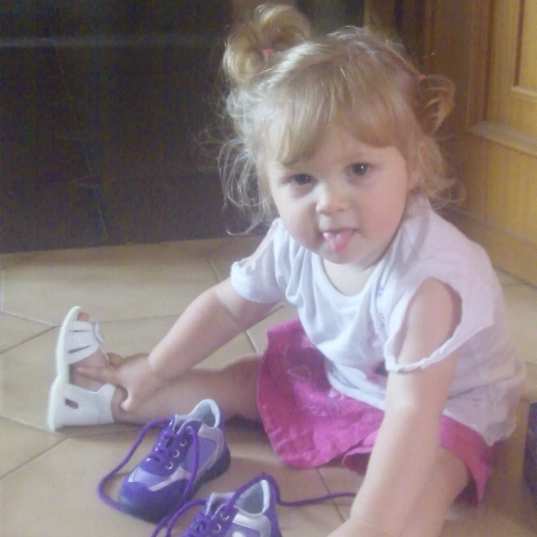 Bambina seduta a terra che gioca con le scarpe